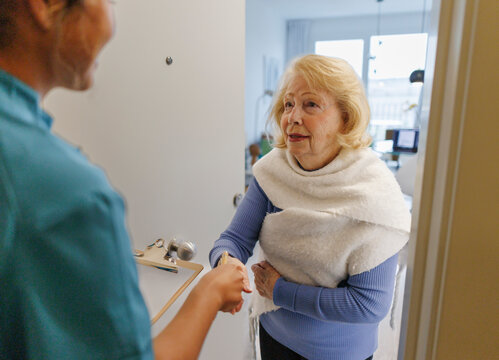 Nurse greeting woman at home for medical checkup and assistance