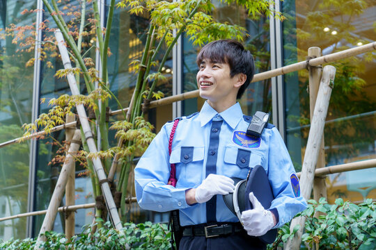 オフィスビルの前に立つ若い日本人男性警備員　撮影協力：学校法人電波学園　東京電子専門学校