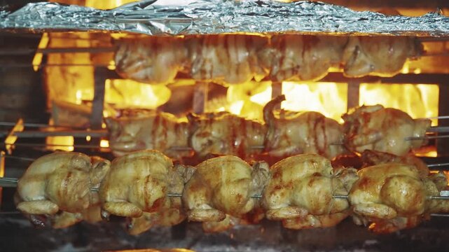 Golden Rotisserie Chickens Roasting Over Open Flames