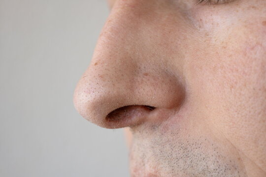 Macro close up of an unrecognizable Caucasian man's nose showing skin pores and natural freckles