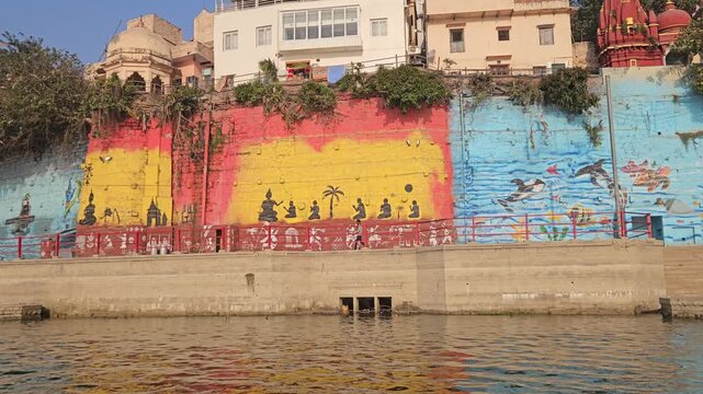 Riverside view of Varanasi ghats from a moving boat on the Ganges River. Traditional houses, boats, and daily life along sacred ghat, capturing authentic Indian culture and spiritual atmosphere.