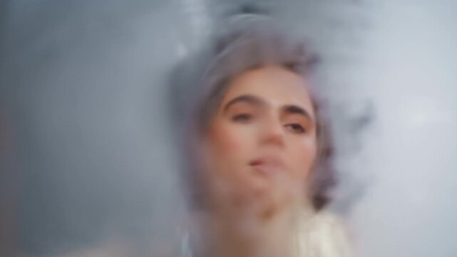 Woman wiping bathroom mirror glass closeup. Young pretty looking hazy reflection