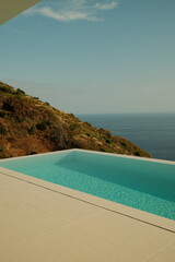 Modern infinity pool overlooking the Atlantic ocean and rocky cliffs. © Anastasiia