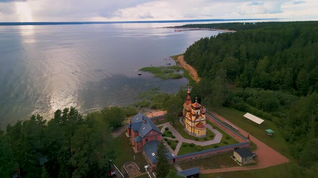 Epic Ladoga lake monastery aerial orbit. 
Cinematic 4K drone panorama of historic 
orthodox Christian skete and isolated 
forest coastline on Konevets island, Russia.
