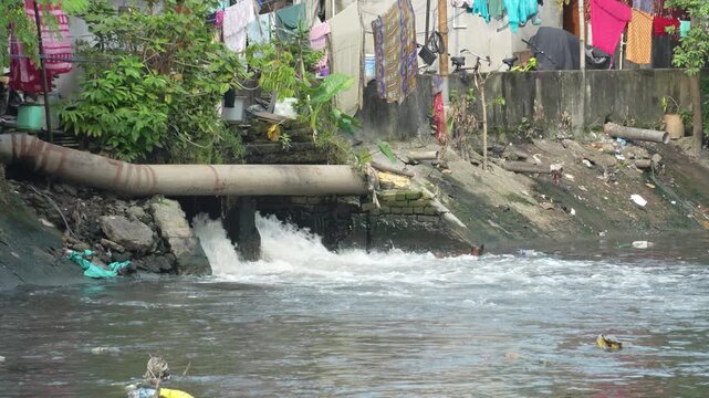 Small nala flowing into a river near a rural village in India, showing natural water stream, greenery and peaceful countryside environment.