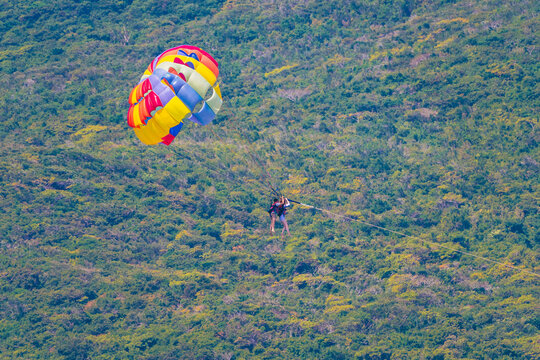 People fly on parachute during parasailing in summer on vacation over the sea