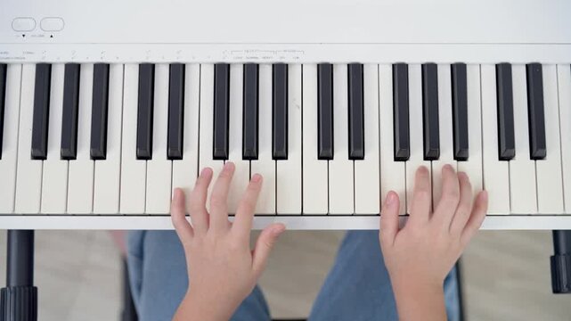 Young Child Playing Keyboard Perspective Focus on Hands Enthusiastically Pressing Piano Keys in a Bright and Inviting Room Setting