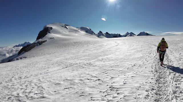 POV mountaineering in rope team with mountaineer and mountain glacier panorama with summits Gendarm, Lyskamm, Castor and pan shot towards Breithorn in Swiss Alps, canton of Valais, Switzerland