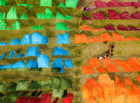 Narayanganj, Bangladesh - 30 March 2026: Aerial view of vibrant textiles arrayed on the grass, a symphony of colour and pattern creating a vivid spectacle.