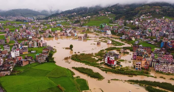 Aerial shot capturing the severe monsoon flood disaster across Banepa Nepal with vast areas of urban buildings residential homes and agricultural farming land completely submerged by water.