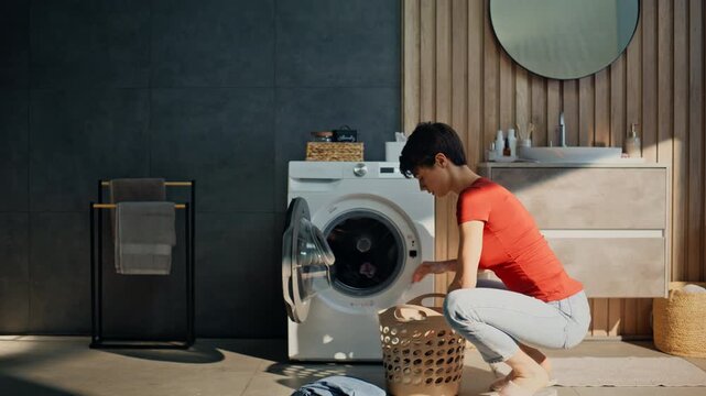 Pretty girl sorting clothes putting laundry drum. Woman loading washing machine