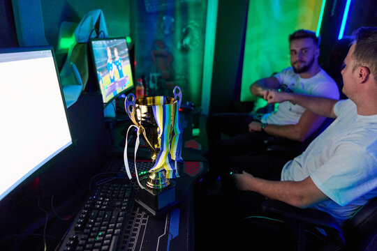 Friends Celebrating Esports Victory With Trophy in Neon Gaming Room During Competitive Match