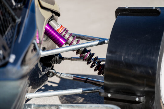 High performance automotive suspension system featuring purple coilover shock absorber and silver control arms on a professional racing vehicle for engineering and mechanical industry