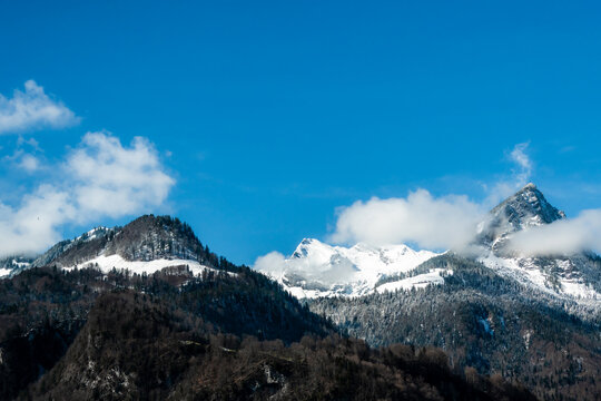 View of snow-dusted peaks pierce the vibrant blue sky, a tranquil scene unfolding from the train window, Train from Lucerne to Interlaken, Switzerland.