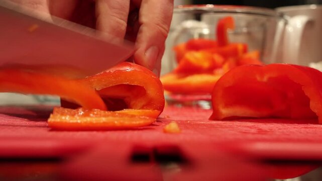 Chef cutting fresh colorful bell peppers on red cutting board - cooking preparation footage
