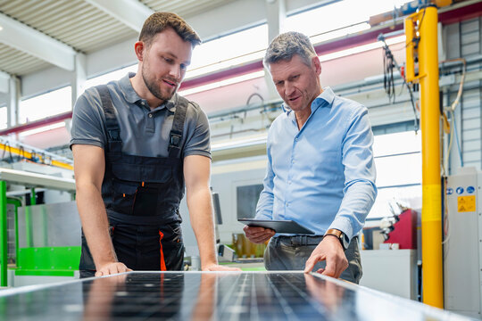 Business meeting at photovoltaic production hall with solar panel