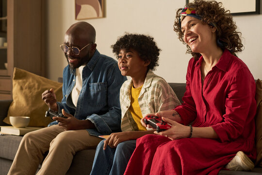 Family playing video game together on couch at home enjoying leisure