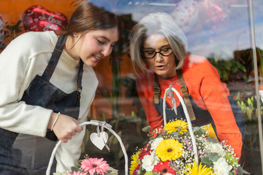 Florist and apprengtice selecting bouquet in flower shop interior