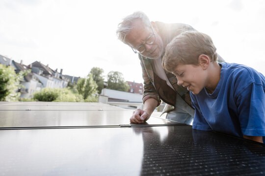 Family inspecting solar panel installation on roof outdoors