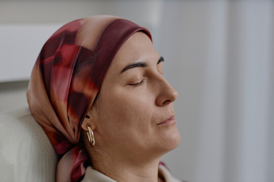 Portrait of person with headscarf resting during cancer recovery
