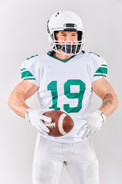 Full-length portrait of American football player in uniform holding ball