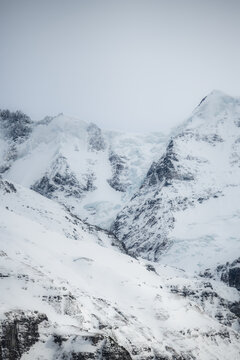 View of snow-laden peaks pierce the sky, a symphony of white and grey, where nature's grandeur meets the serene stillness of a winter's day, Murren, Switzerland.