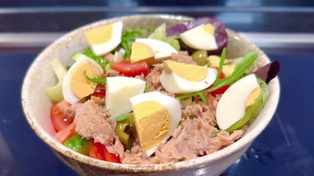 close up of salad bowl containing lettuce boiled eggs tuna tomatoes and lettuce
