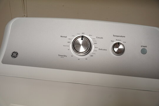 Modern GE washing machine and dryer control panels featuring chrome dials, cycle settings, and branding for domestic laundry concepts.