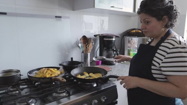 Hispanic woman in apron turning frying plantains in a pan