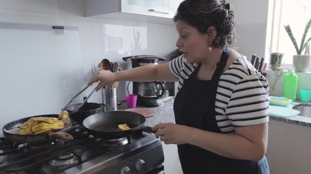Mature Latina woman frying plantains on a gas stove and talking
