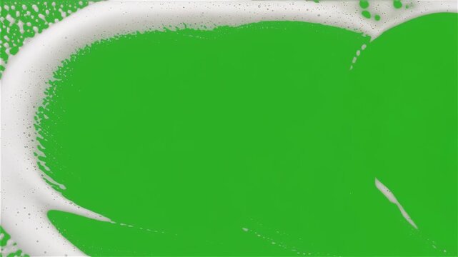 Hand Using a Yellow Sponge to Wipe and Clear White Soap Suds off a Green Screen Surface, Top Down View