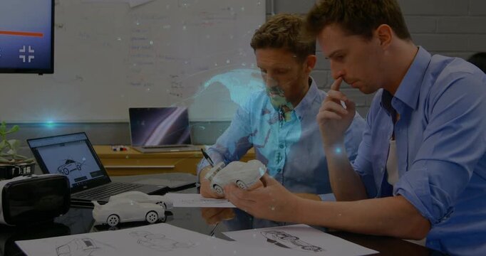 Right peer lifting car proto holo globe appearing left peer watching and noting sketches for review