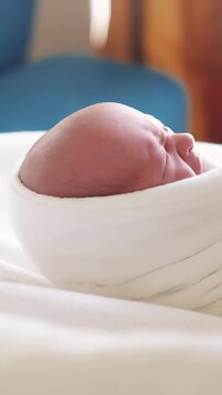 A baby is wrapped in a soft blanket, lying on a bed. The baby is crying softly, creating a serene atmosphere in the cozy room.