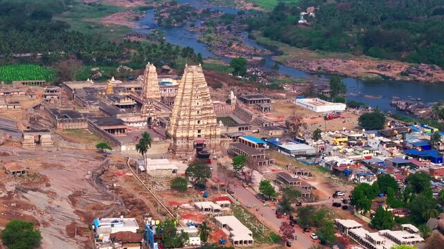 Virupaksha Temple with Tungabhadra river, trees and small business shops at hampi, karnataka, india. day time, semi orbit shot, drone shot, 4k.