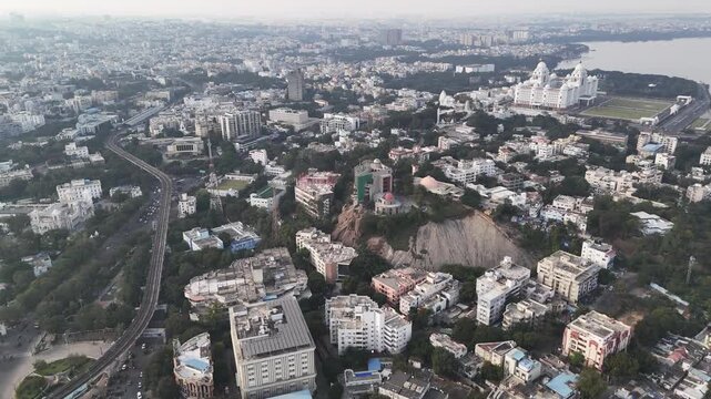 Wide cinematic aerial of Hyderabad highlighting urban density, mixed architecture, and green pockets, with the iconic Birla Mandir rising above the surrounding cityscape.