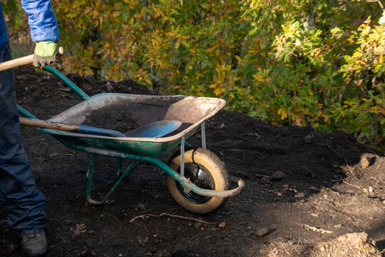 Green Wheelbarrow on a Dirt Pile The Concept of Gardening Activity.