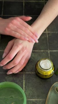 Woman's fingers dipping into a jar of moisturizing white cream, skincare routine with aloe vera