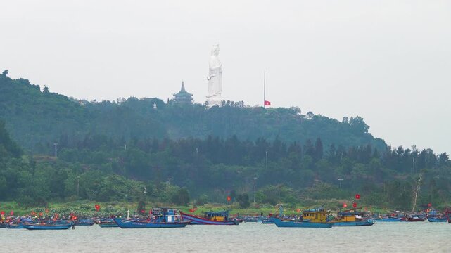 Statue of a female Gautama Siddhartha Budda at Lin Ung Temple in Da Nang. The coast of the South China Sea with many junks. Vietnam