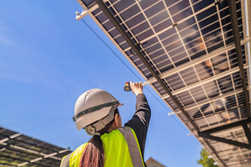 Fototapeta premium Engineer inspecting solar panels under a solar-powered carport on a sunny day, ensuring optimal performance. Focus on renewable energy, sustainability, green power, and eco-friendly solar solutions.