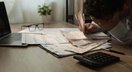 Person holding receipts and reviewing financial documents with calculator during expense tracking and budgeting process, showing financial stress in accounting analysis and personal finance management