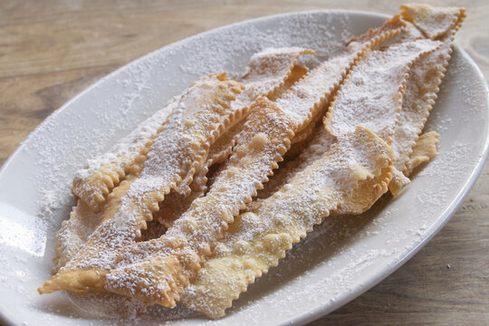 Italian Carnival fritters chiacchiere with powdered sugar on white plate