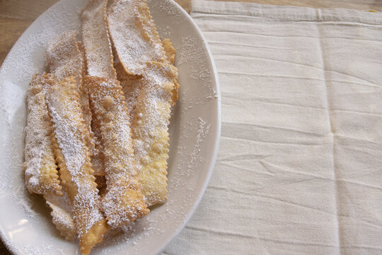 Italian Carnival fritters chiacchiere with powdered sugar on white plate