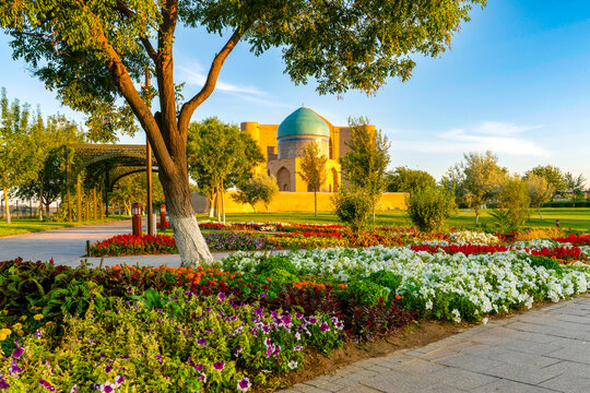 Turkestan, Kazakhstan - June 03, 2025: Scenic early morning sunrise view of the historical Rabia Sultan Begim Mausoleum framed by a park pathway and vibrant spring flowers