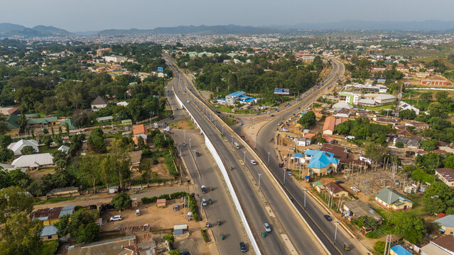 Aerial view of a modern highway cutting through the lush landscape, connecting the city with vibrant greens and distant hills, Jos, Plateau, Nigeria.