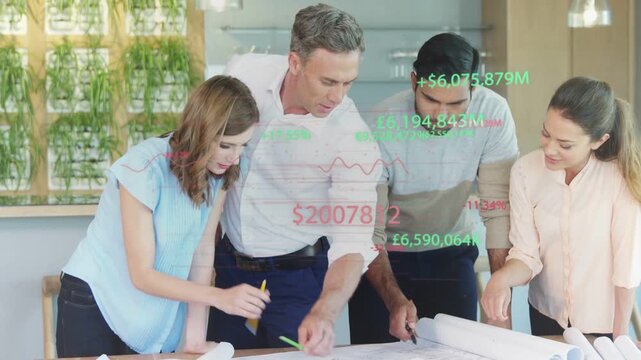 Design team leaning around table in studio kitchen, pointing to rolled plans with pencils and pen