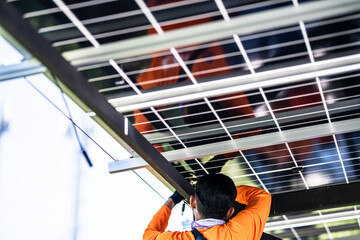 Fototapeta premium A technician in an orange safety jacket working on the wiring and connections of a solar panel system installed on a steel carport structure. The worker is focused on maintenance or installation.