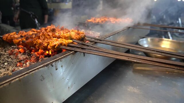 Juicy chicken grilling over coals with smoke and char marks, grilled food concept