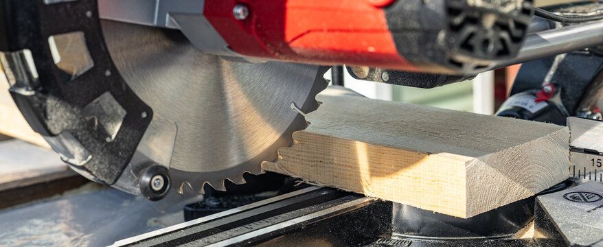 Miter saw tool blade up close for cutting lumber and carpentry. Using a circular saw to cut a wooden board. Blade of a miter saw to cut off the edge of a wooden board, close up.