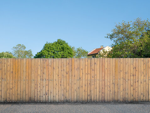 Suburban house behind wooden fence in quiet neighborhood