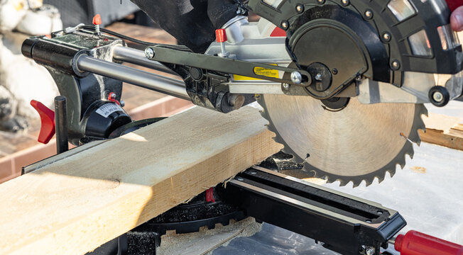 Miter saw tool blade up close for cutting lumber and carpentry. Using a circular saw to cut a wooden board. Blade of a miter saw to cut off the edge of a wooden board, close up.
